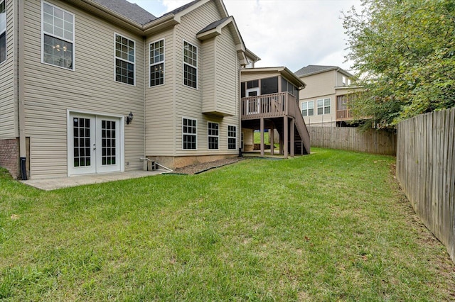 back of house with french doors, a wooden deck, and a lawn