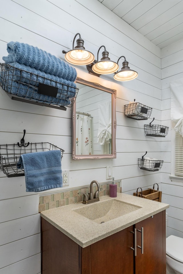 bathroom with toilet, vanity, and wooden walls