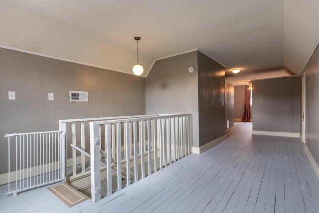 hallway featuring vaulted ceiling, crown molding, and wood-type flooring