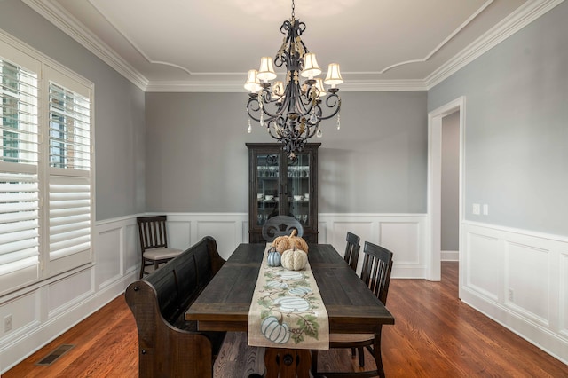 dining area with dark hardwood / wood-style flooring, crown molding, and a chandelier