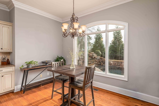 dining room with light wood-type flooring, an inviting chandelier, a healthy amount of sunlight, and crown molding