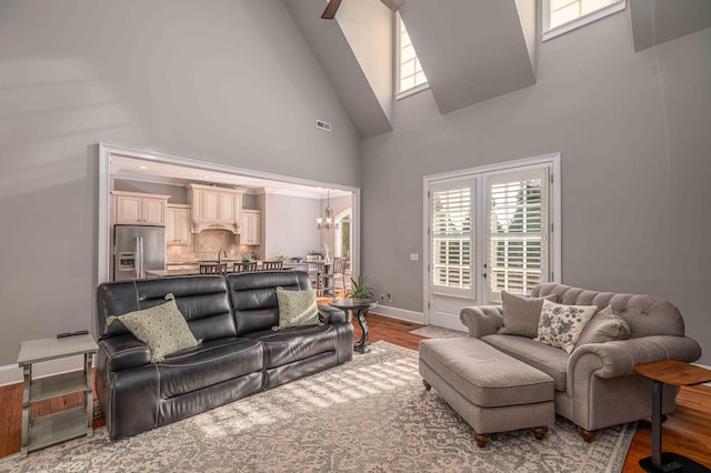 living room featuring a towering ceiling, wood-type flooring, and an inviting chandelier