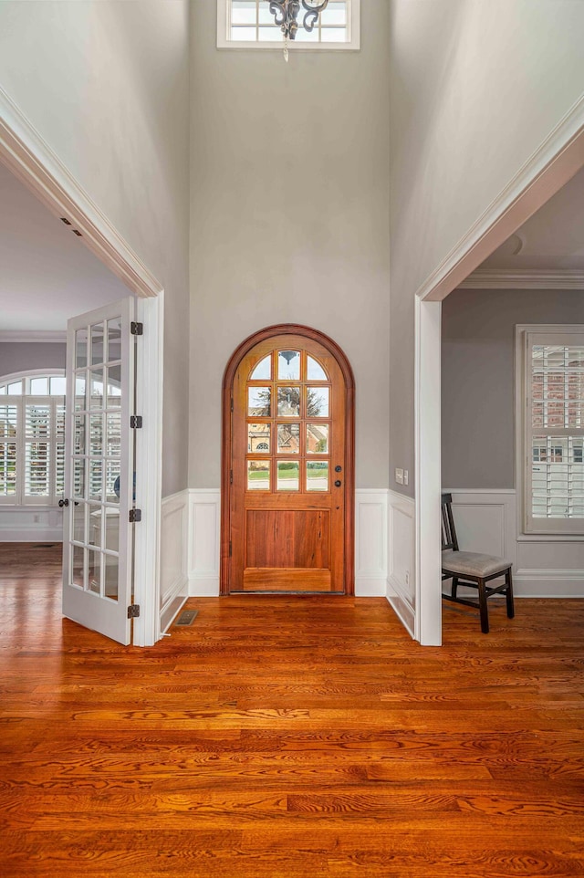 foyer with hardwood / wood-style floors, crown molding, and a high ceiling