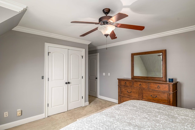 bedroom featuring ceiling fan, light colored carpet, ornamental molding, and a closet