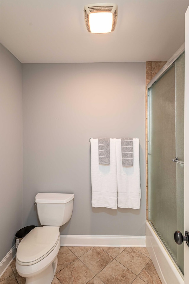 bathroom featuring combined bath / shower with glass door, tile patterned floors, and toilet