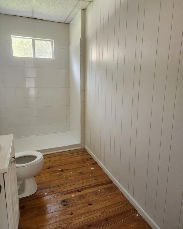 bathroom with vanity, a shower, hardwood / wood-style floors, toilet, and wood walls