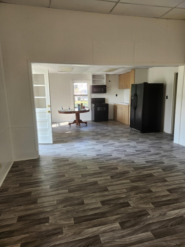 unfurnished living room featuring a paneled ceiling and dark hardwood / wood-style flooring