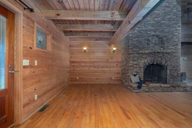 unfurnished living room with wooden ceiling, beamed ceiling, hardwood / wood-style floors, wooden walls, and a fireplace