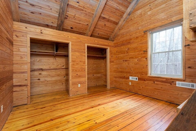 unfurnished bedroom with lofted ceiling with beams, wooden walls, wood ceiling, and light wood-type flooring