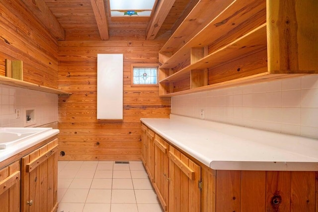 kitchen featuring a skylight, wood walls, light tile patterned flooring, and wooden ceiling