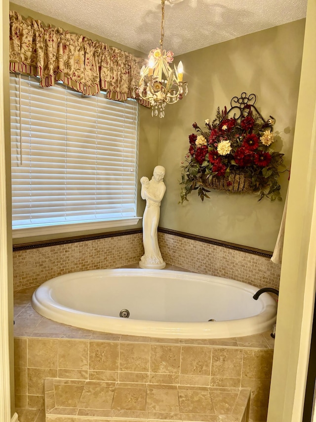 bathroom featuring tiled tub, a chandelier, and a textured ceiling