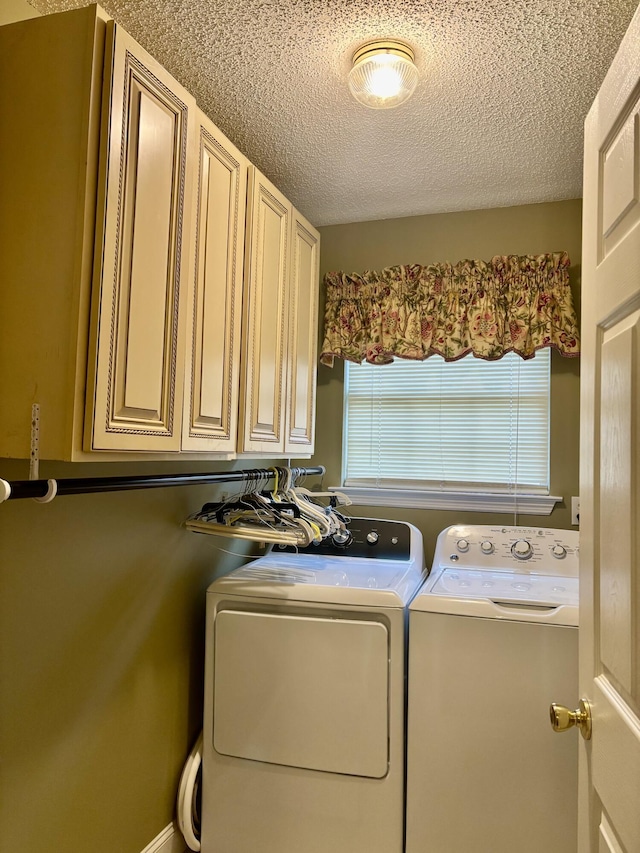 clothes washing area featuring a textured ceiling, cabinets, and washing machine and clothes dryer