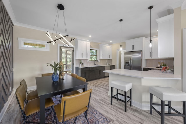 kitchen featuring decorative backsplash, white cabinetry, stainless steel fridge with ice dispenser, and sink