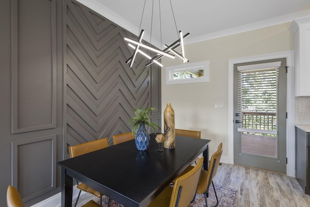 dining space with light hardwood / wood-style floors, an inviting chandelier, and ornamental molding