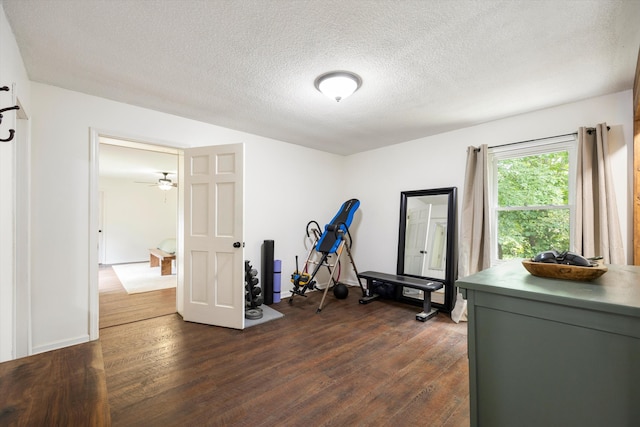 exercise room featuring ceiling fan, dark hardwood / wood-style flooring, and a textured ceiling