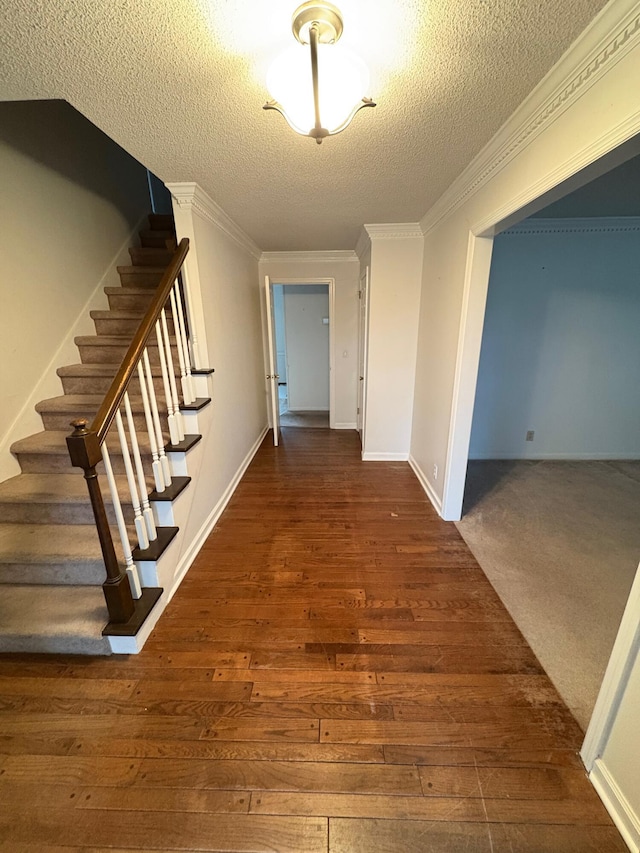 hall featuring dark hardwood / wood-style floors, a textured ceiling, and ornamental molding