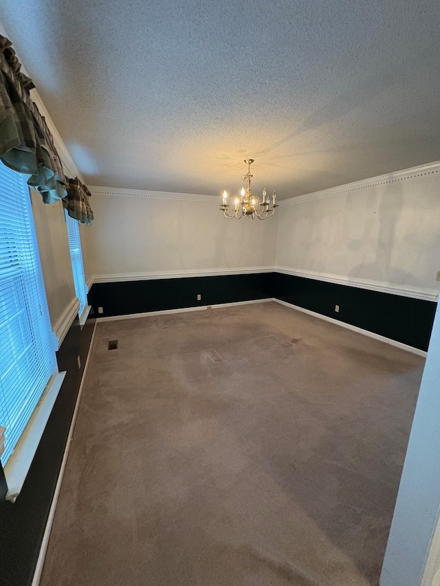 carpeted spare room with crown molding, a textured ceiling, and an inviting chandelier