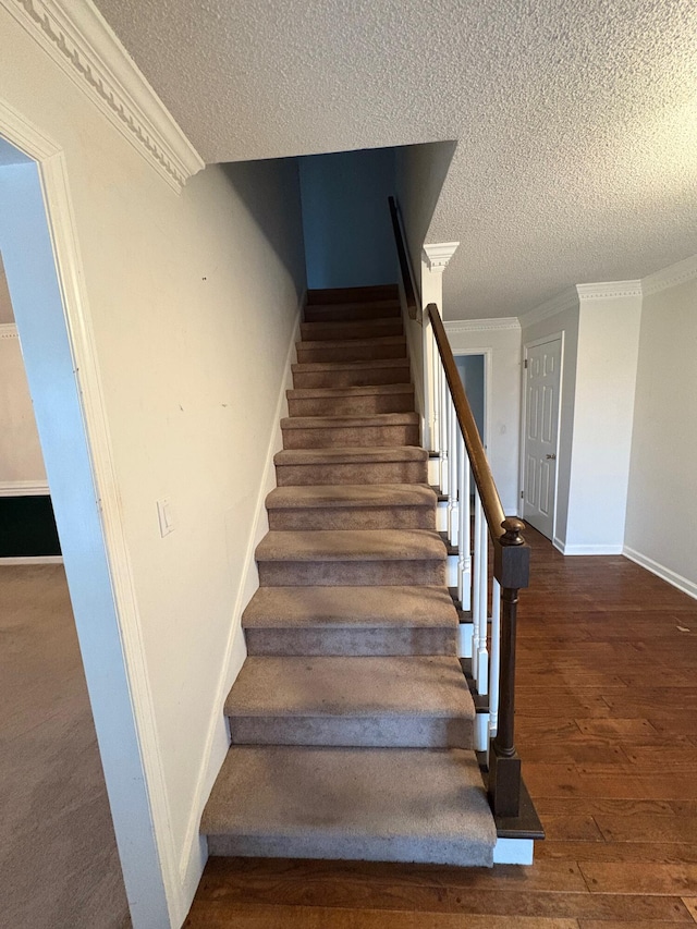 stairs featuring crown molding, a textured ceiling, and hardwood / wood-style flooring