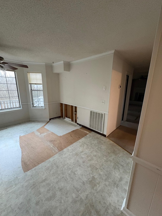 spare room with a textured ceiling, ceiling fan, and crown molding