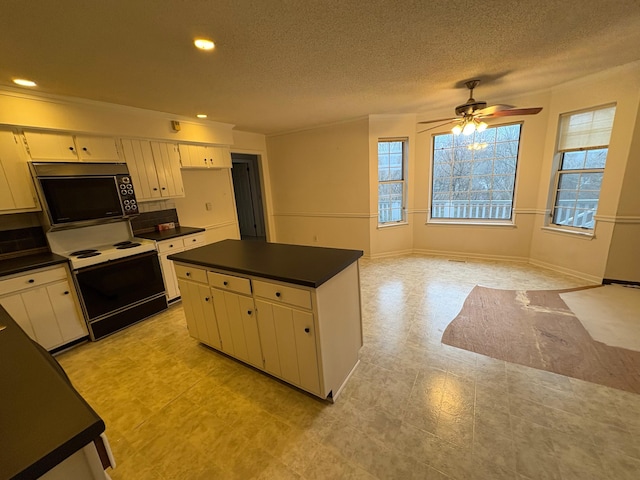 kitchen with ceiling fan, a center island, white electric range, a textured ceiling, and white cabinets