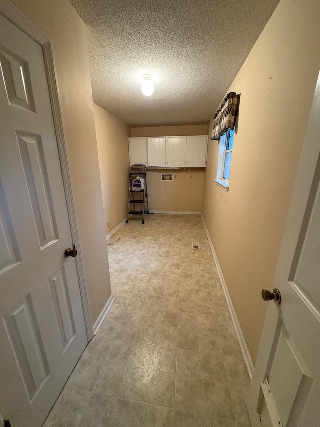 laundry room featuring cabinets and a textured ceiling