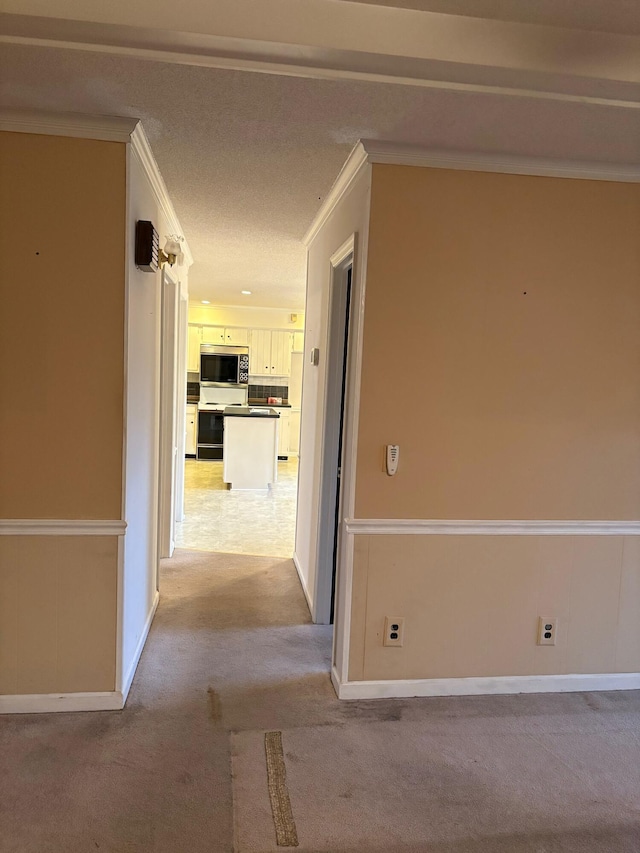 corridor with crown molding and light carpet