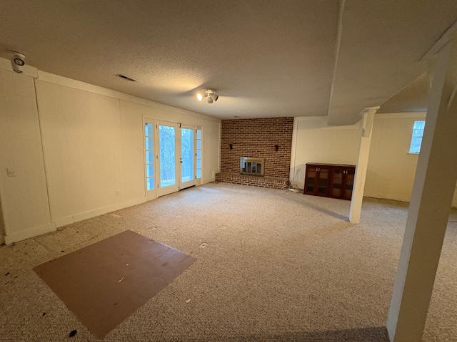 unfurnished living room with a textured ceiling and a brick fireplace