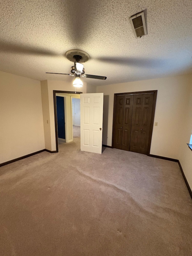 unfurnished bedroom with carpet flooring, ceiling fan, a textured ceiling, and a closet