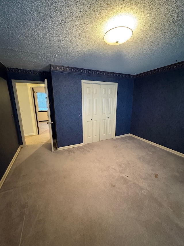 unfurnished bedroom featuring carpet flooring, a textured ceiling, and a closet