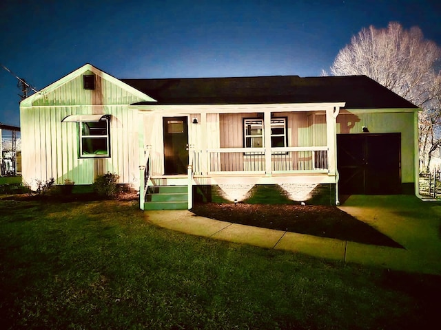 ranch-style house featuring a porch, a garage, and a front lawn