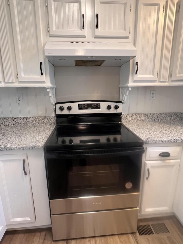 kitchen with extractor fan, tasteful backsplash, white cabinetry, electric range, and light stone countertops