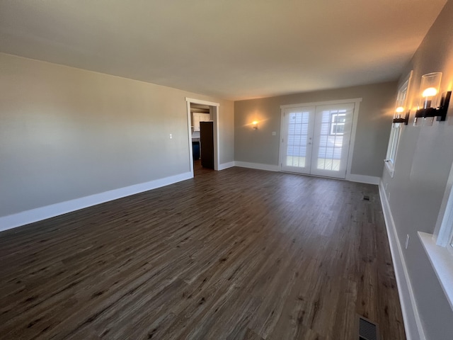 unfurnished living room featuring dark wood-type flooring and french doors