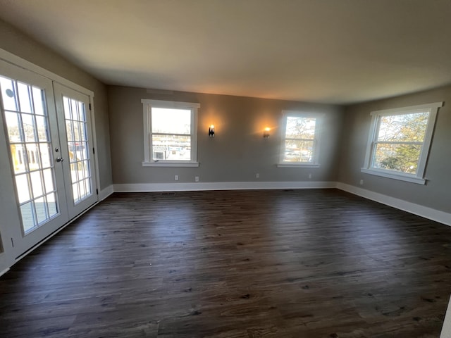 spare room featuring a healthy amount of sunlight, dark hardwood / wood-style floors, and french doors