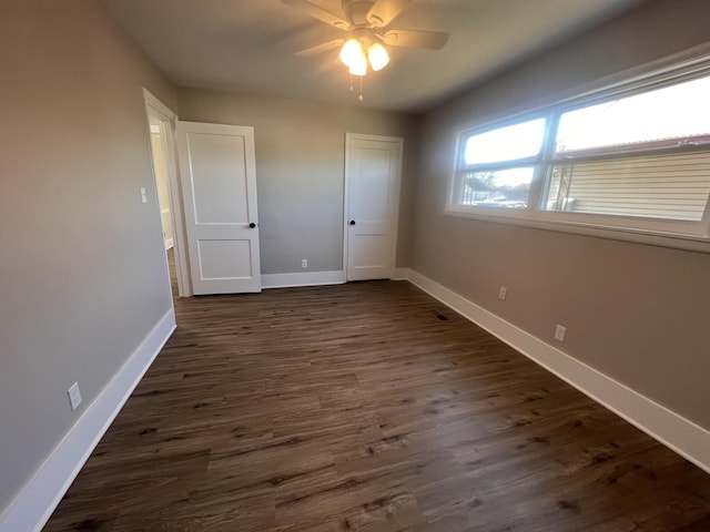 unfurnished bedroom featuring dark wood-type flooring and ceiling fan