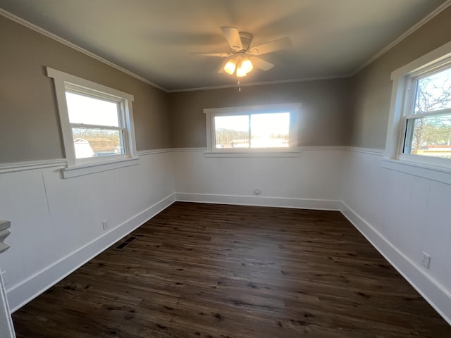 empty room with dark hardwood / wood-style flooring, ceiling fan, crown molding, and a healthy amount of sunlight