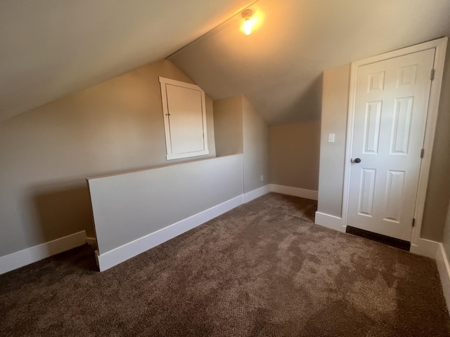 additional living space with vaulted ceiling and dark colored carpet