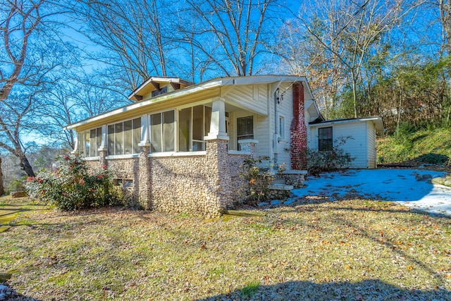 view of side of property featuring a sunroom and a lawn