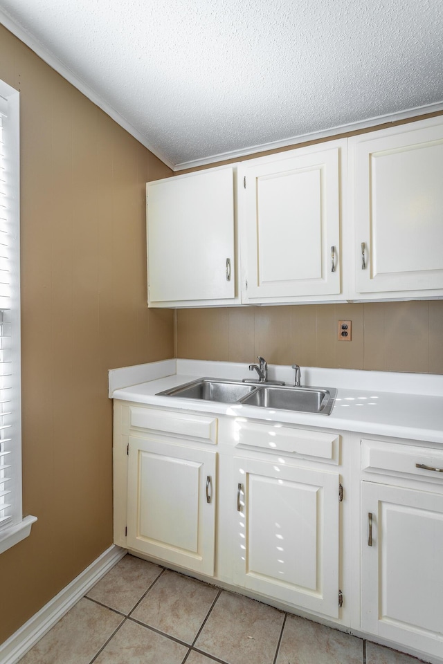 laundry area featuring light tile patterned floors, sink, and a textured ceiling