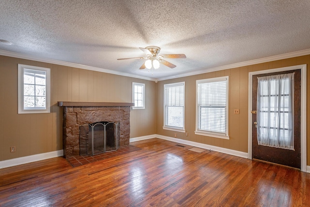 unfurnished living room featuring ceiling fan, dark hardwood / wood-style floors, crown molding, and a stone fireplace