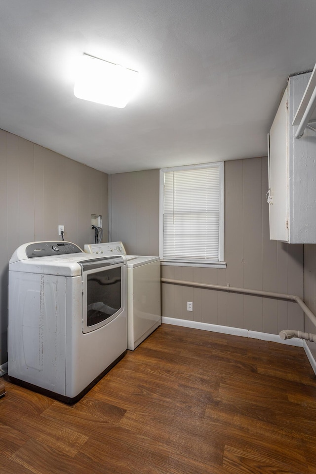 laundry room with dark hardwood / wood-style flooring, washing machine and clothes dryer, and cabinets