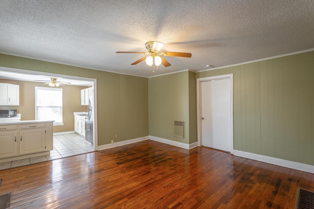 unfurnished living room featuring a textured ceiling, ceiling fan, crown molding, and light hardwood / wood-style flooring