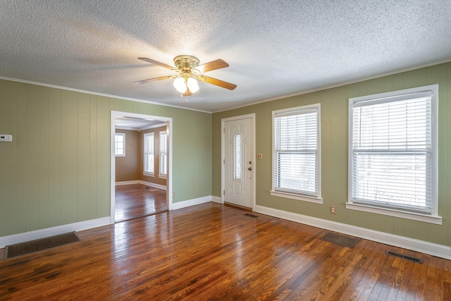 interior space with ceiling fan, a healthy amount of sunlight, dark wood-type flooring, and crown molding