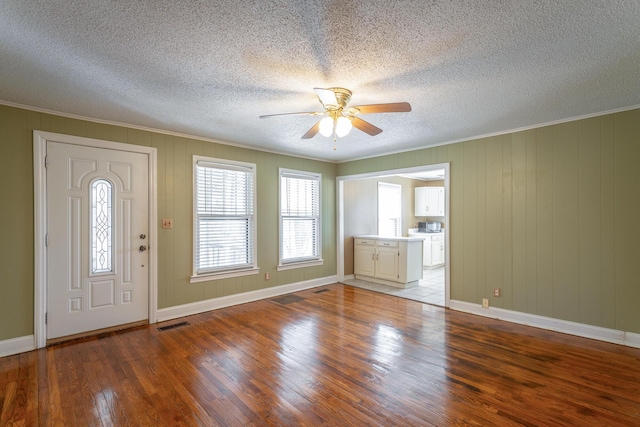 entryway featuring wooden walls, ceiling fan, light wood-type flooring, a textured ceiling, and crown molding