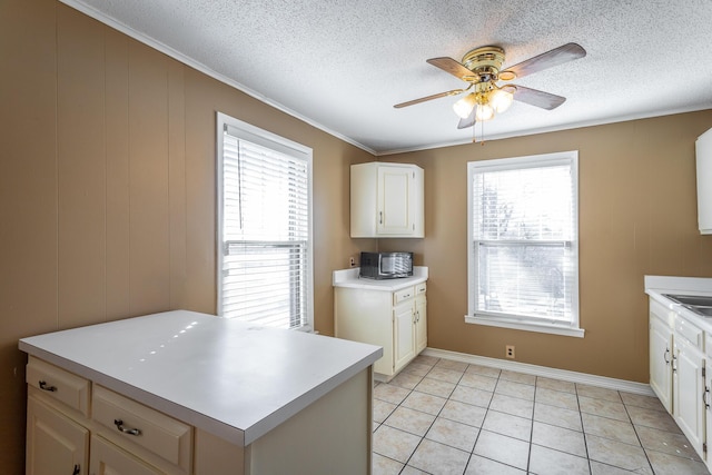 kitchen featuring a textured ceiling, white cabinetry, ornamental molding, ceiling fan, and light tile patterned floors