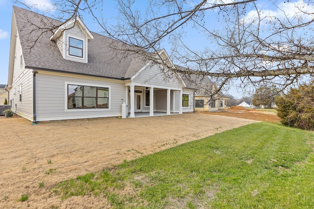 rear view of property with central air condition unit and a lawn