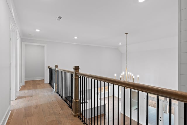 hall featuring ornamental molding, light hardwood / wood-style floors, vaulted ceiling, and a notable chandelier