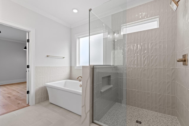 bathroom with tile patterned flooring, separate shower and tub, tile walls, and ornamental molding