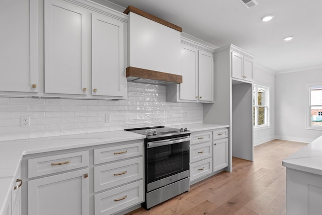 kitchen featuring stainless steel range with electric stovetop, light stone countertops, light wood-type flooring, tasteful backsplash, and white cabinetry