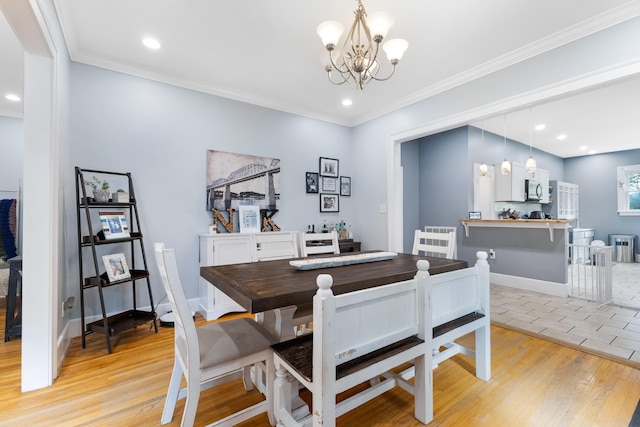 dining area with a notable chandelier, crown molding, and light hardwood / wood-style flooring