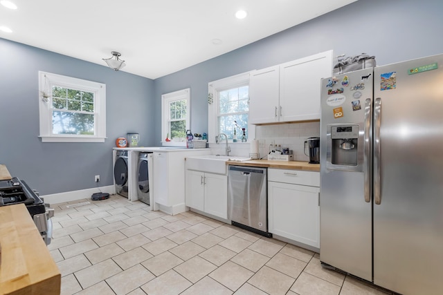 kitchen featuring stainless steel appliances, sink, separate washer and dryer, white cabinets, and butcher block countertops